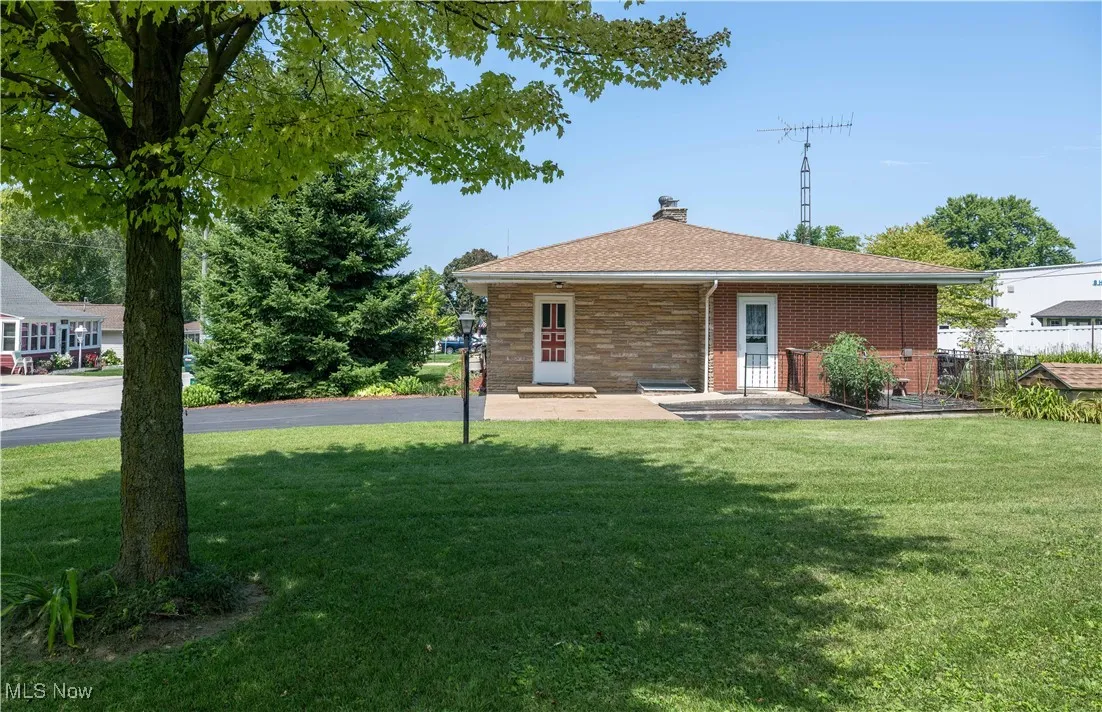 Rear view of house featuring a chimney, brick siding, and a shingled roof