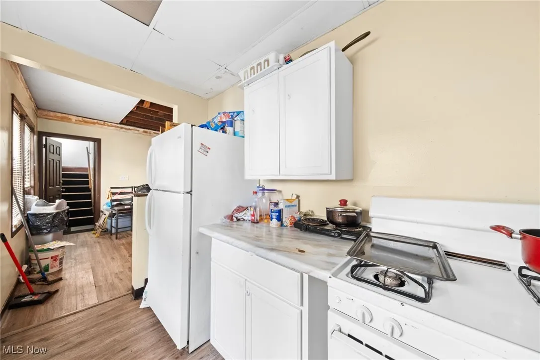 Kitchen with white appliances, light countertops, and white cabinets