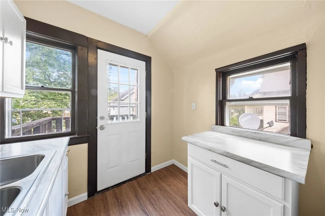 Doorway with healthy amount of natural light, vaulted ceiling, and wood finished floors
