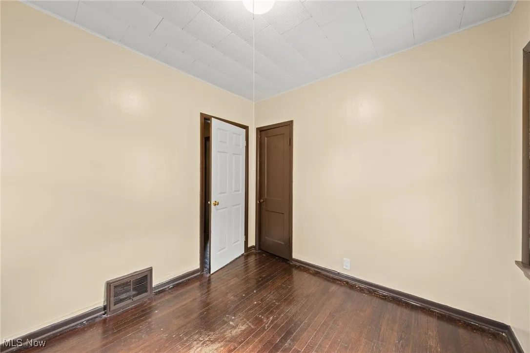 Empty room with dark wood-type flooring and baseboards
