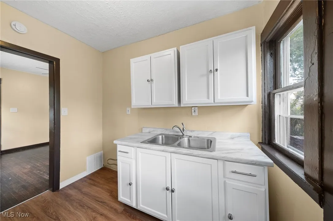 Kitchen with white cabinets, light countertops, dark wood finished floors, and a textured ceiling