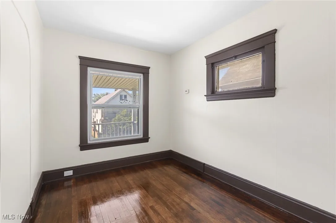 Spare room with dark wood-type flooring and baseboards