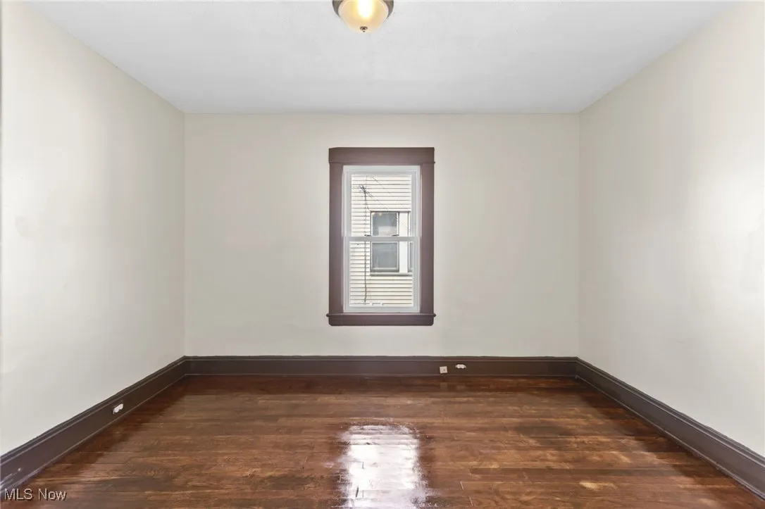 Unfurnished room with dark wood finished floors and baseboards