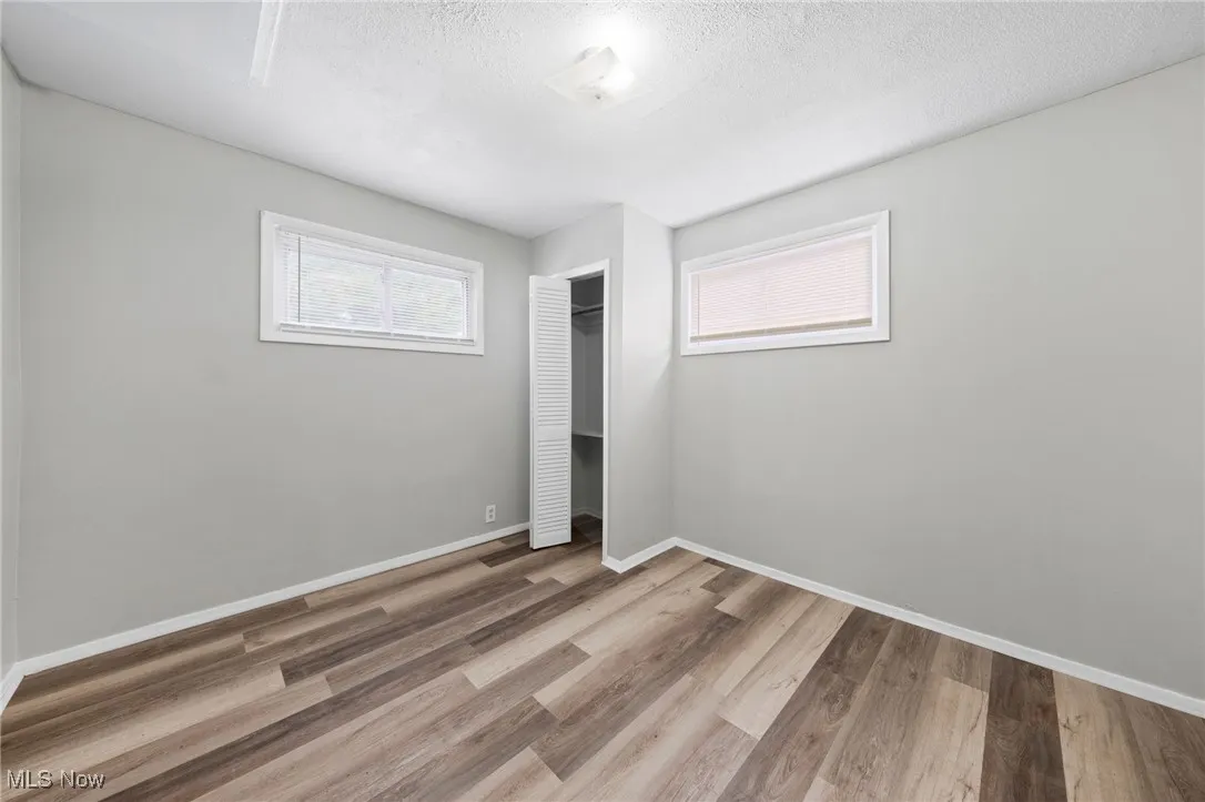 Unfurnished bedroom with a closet, light wood-style flooring, and a textured ceiling