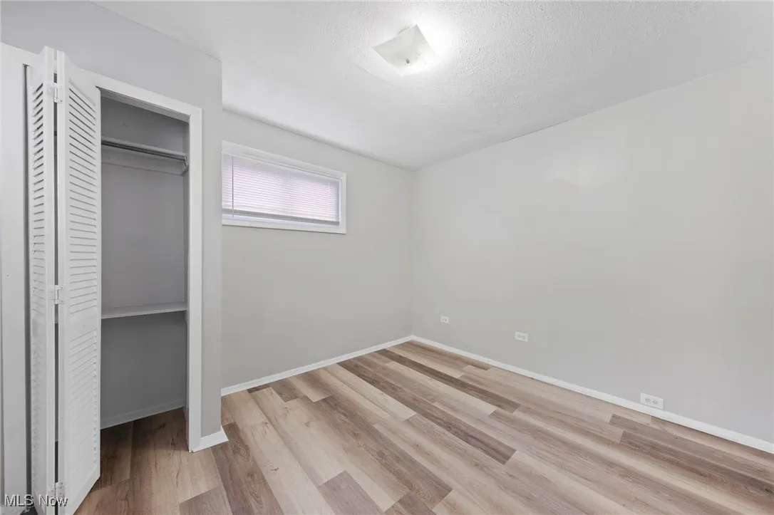 Unfurnished bedroom with light wood-style floors, a textured ceiling, and a closet