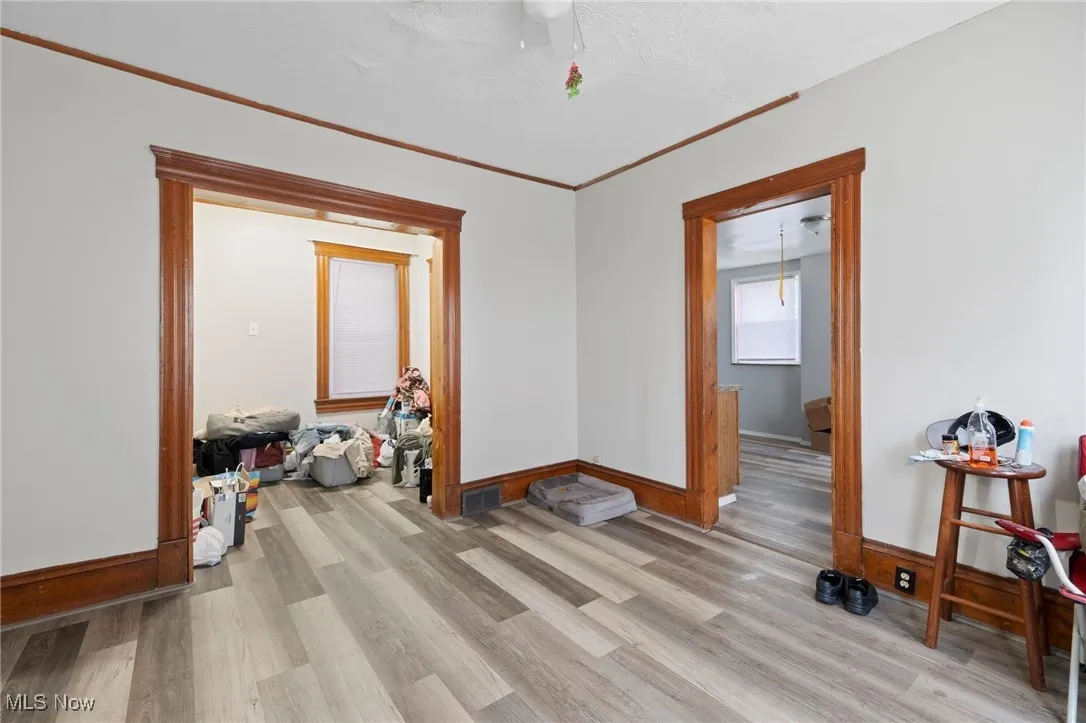 Empty room featuring light wood finished floors and crown molding