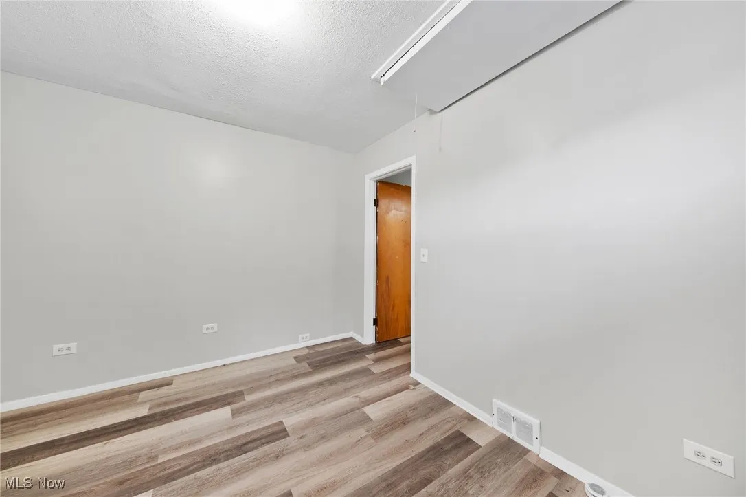 Spare room featuring attic access, light wood-type flooring, and a textured ceiling