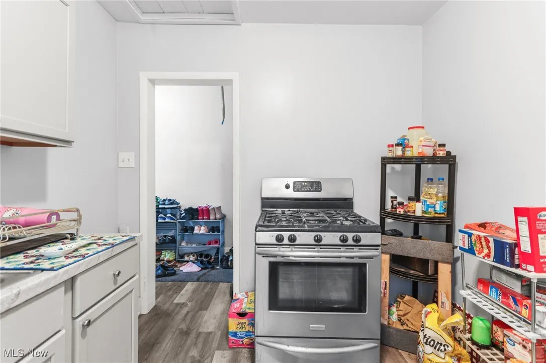 Kitchen with gas stove, dark wood finished floors, light countertops, and white cabinetry