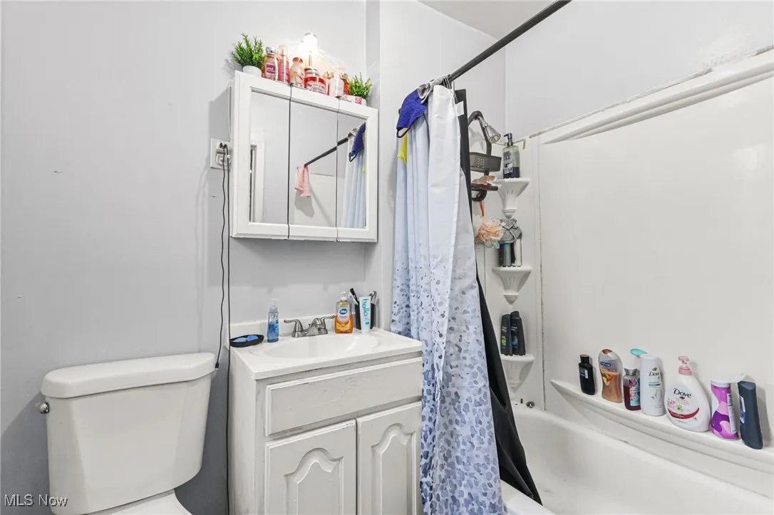 Bathroom featuring shower / tub combo with curtain and vanity