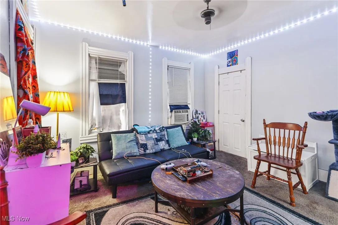 Carpeted living room with ceiling fan and cooling unit
