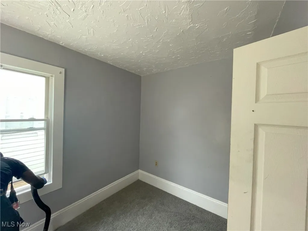 Empty room featuring carpet flooring and a textured ceiling