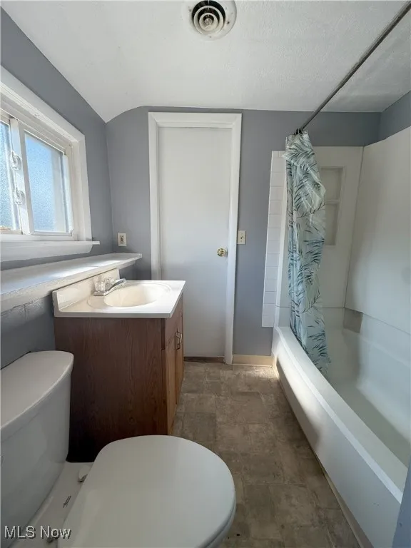 Bathroom featuring shower / tub combo with curtain, vanity, and a textured ceiling