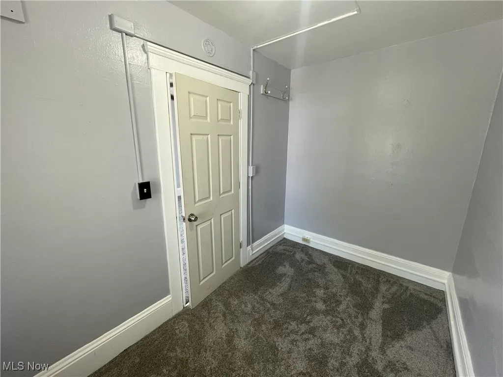 Spare room featuring dark colored carpet and baseboards