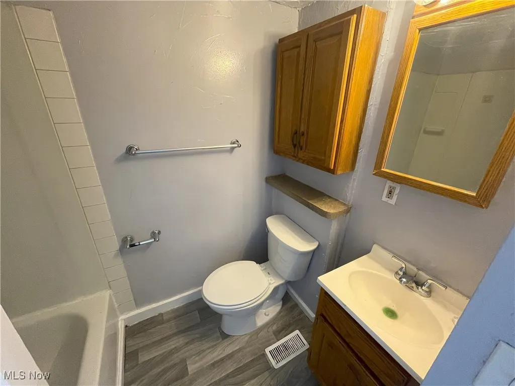 Bathroom with dark wood-style flooring, vanity, and a tub to relax in