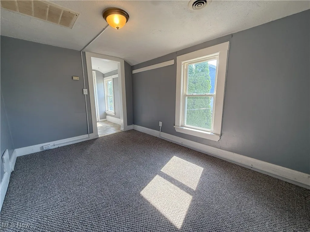 Carpeted spare room with baseboards and lofted ceiling