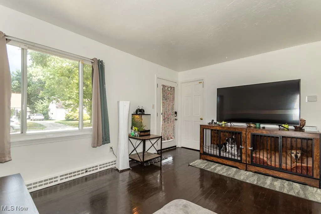 Living room with a baseboard heating unit and dark wood finished floors
