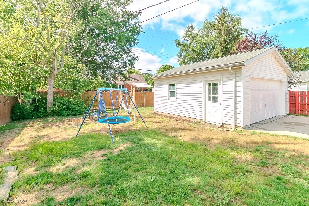 Fenced backyard featuring an outdoor structure, a playground, and a detached garage