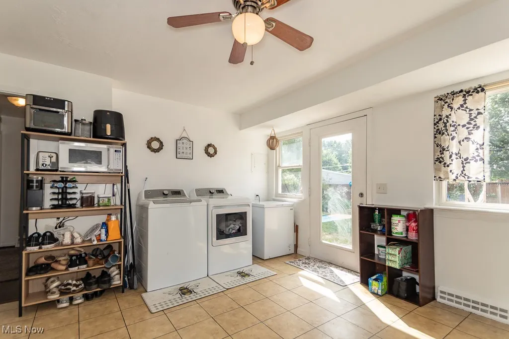 Laundry area featuring light tile patterned flooring, plenty of natural light, washing machine and clothes dryer, and a ceiling fan