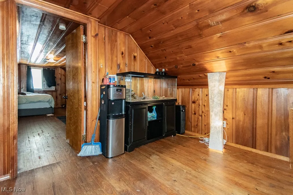 Kitchen with lofted ceiling, wooden walls, wooden ceiling, and hardwood / wood-style floors