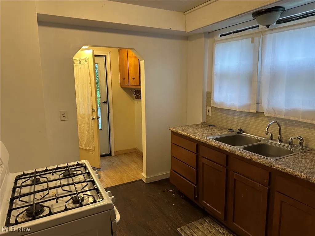Kitchen featuring gas range gas stove, brown cabinets, dark wood-type flooring, and arched walkways