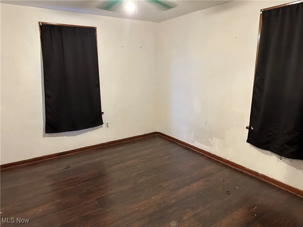 Spare room featuring dark wood-type flooring and a ceiling fan