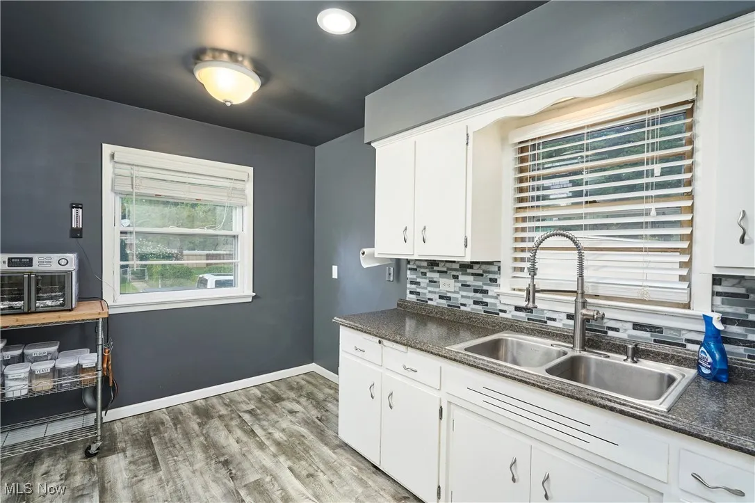 Kitchen featuring dark countertops, light wood-style flooring, white cabinetry, backsplash, and recessed lighting
