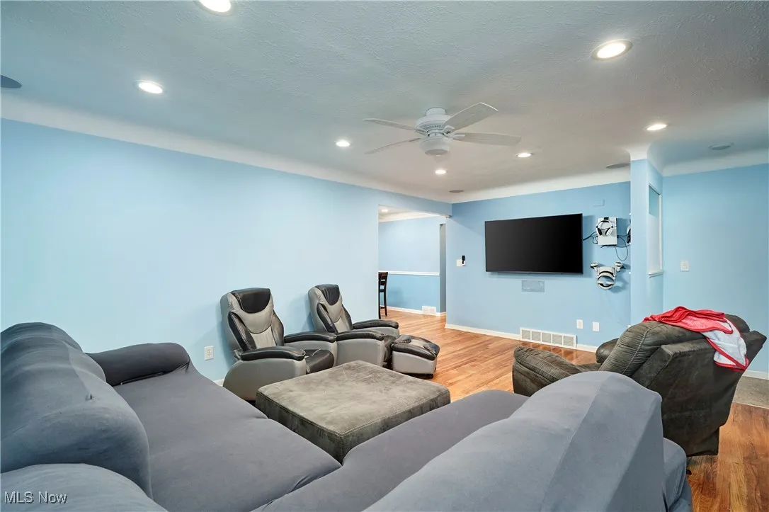 Living room with light wood finished floors, recessed lighting, and a ceiling fan