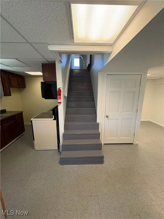 Staircase with tile patterned floors, a paneled ceiling, and washer / clothes dryer