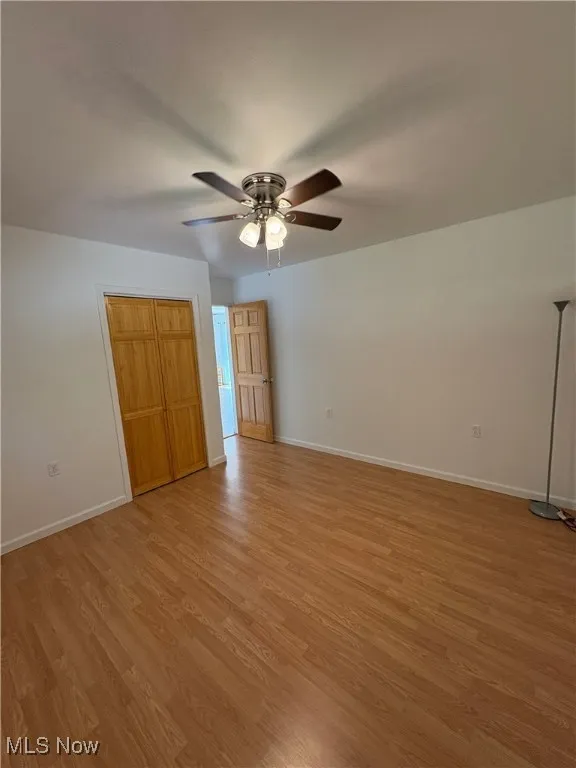 Unfurnished bedroom with light wood-style flooring, ceiling fan, and a closet