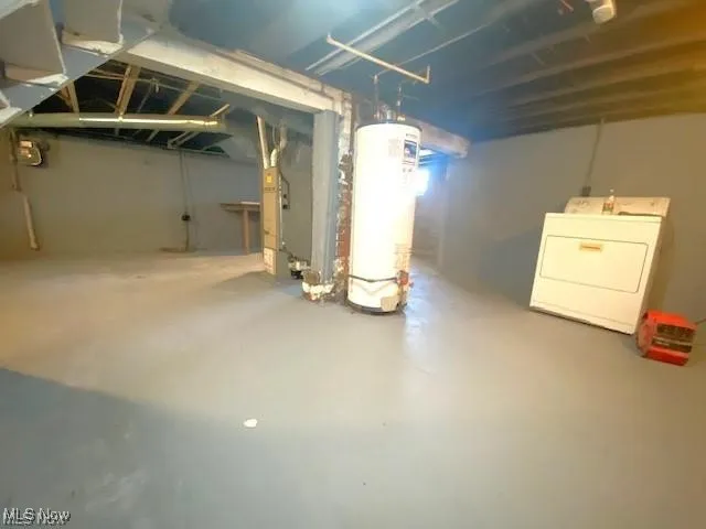 Unfinished below grade area featuring washer / dryer, water heater, and heating unit