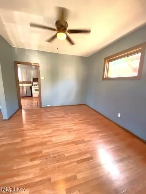 Empty room with a ceiling fan and light wood-style flooring