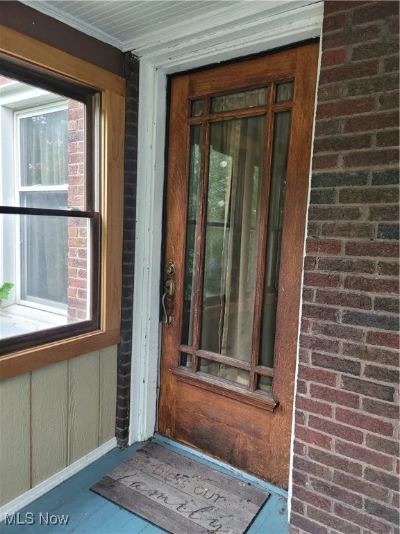 Doorway to property featuring brick siding