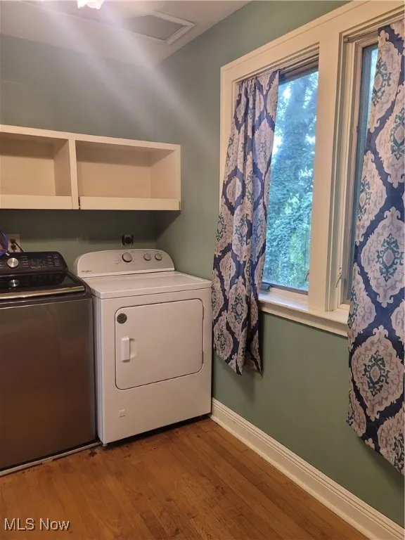Laundry room with healthy amount of natural light, light wood-style flooring, and washing machine and dryer