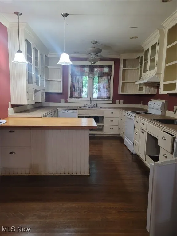Kitchen featuring a peninsula, open shelves, stove, glass insert cabinets, and light countertops