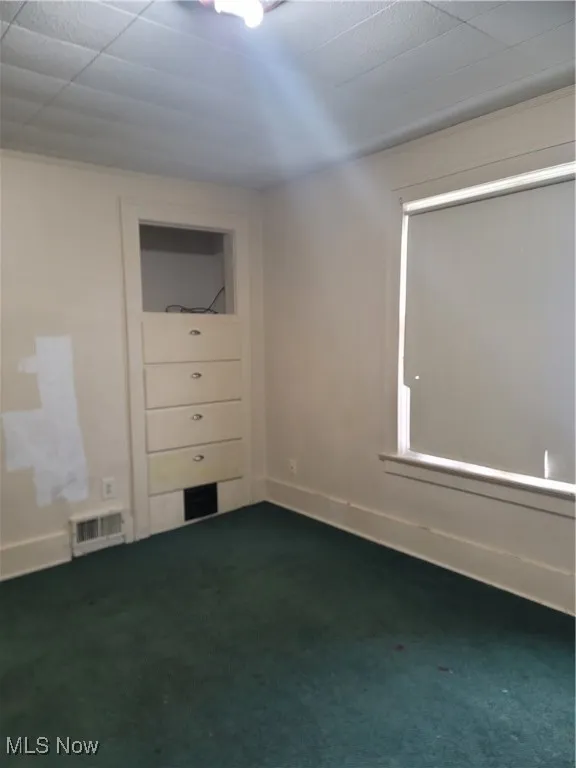 Spare room with dark carpet and baseboards