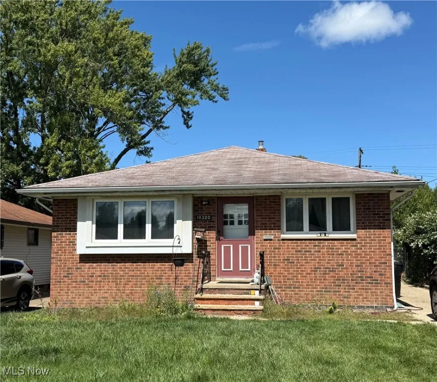 View of front of home featuring a front yard, brick siding, and roof with shingles