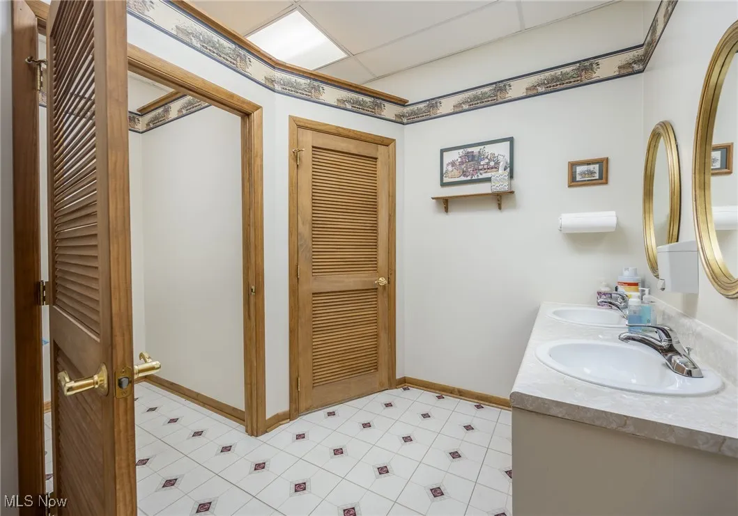 Bathroom with double vanity, a closet, and a paneled ceiling