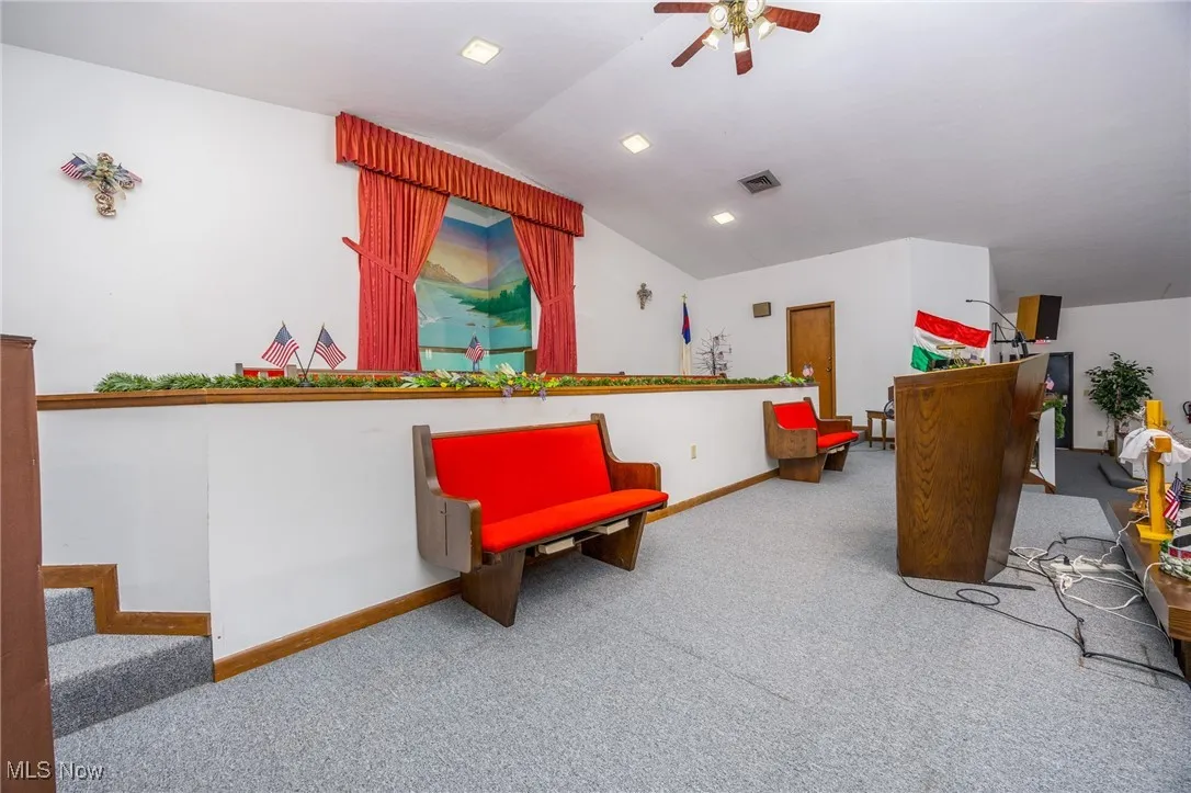 Front of sanctuary featuring carpet flooring, lofted ceiling, a ceiling fan, and stairs