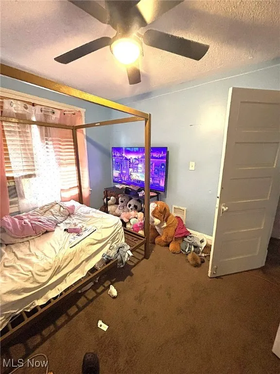 Bedroom featuring a textured ceiling, carpet flooring, and a ceiling fan