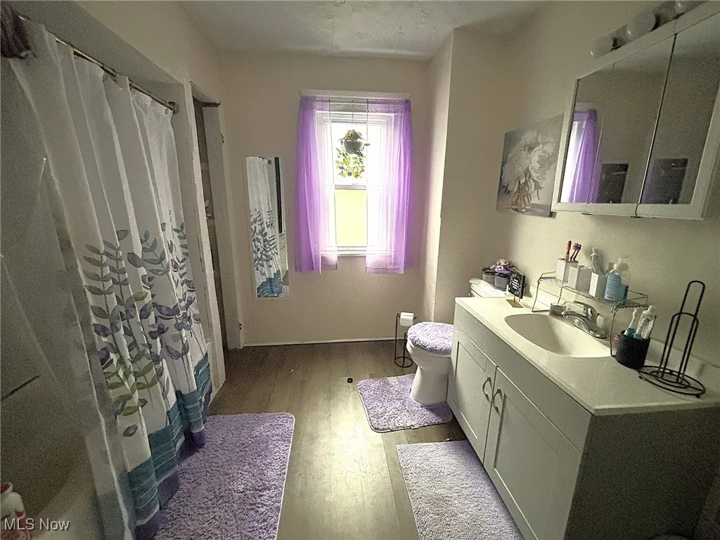 Bathroom featuring light wood finished floors, vanity, and a shower with shower curtain