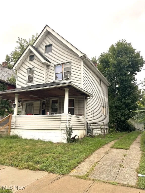 View of front of home featuring covered porch, a front lawn, and a chimney