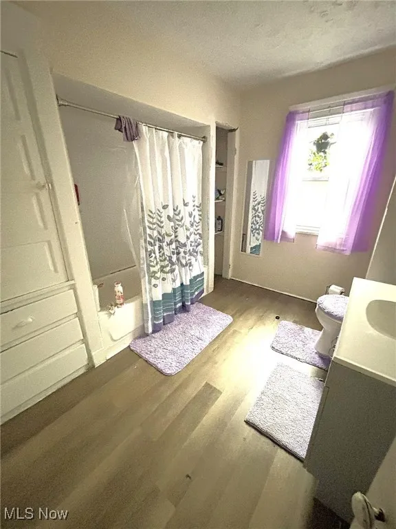 Full bath featuring wood finished floors, vanity, and shower / bath combination with curtain