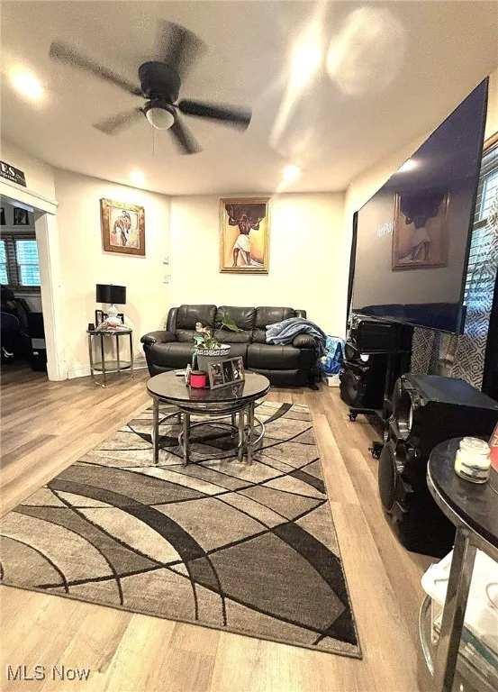 Living room featuring light wood-style floors, a textured ceiling, and ceiling fan
