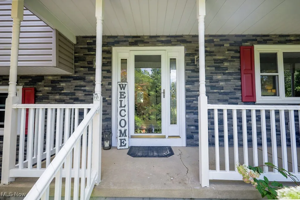 View of exterior entry with covered porch and stone siding