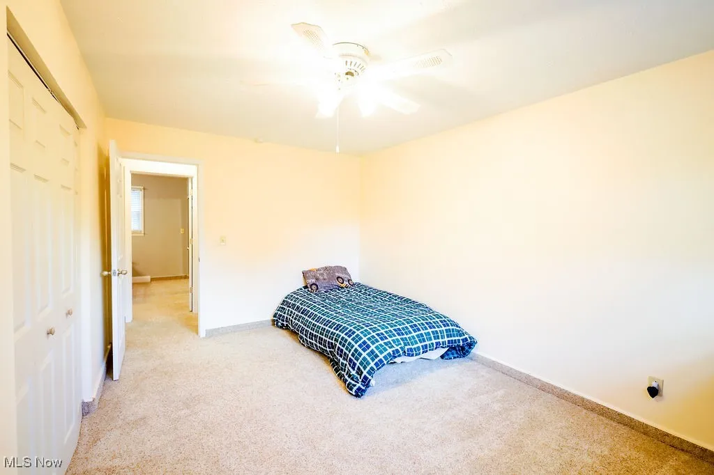 Carpeted bedroom featuring a closet and ceiling fan