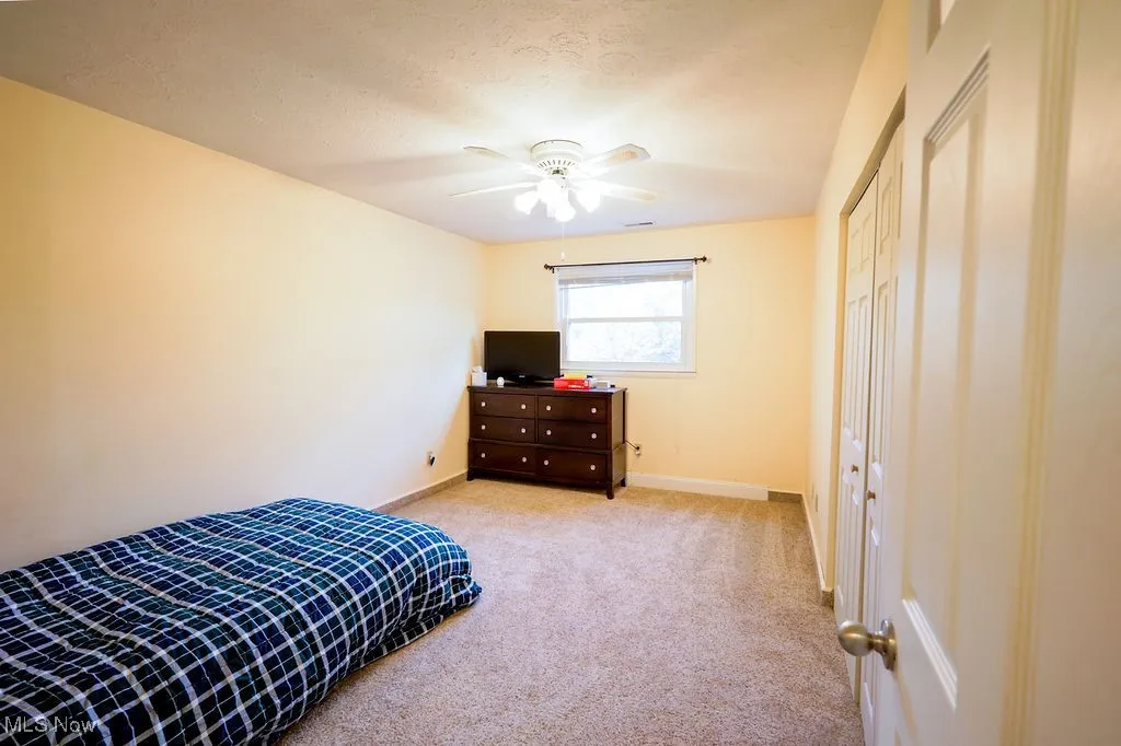 Bedroom featuring light colored carpet, a ceiling fan, and a textured ceiling