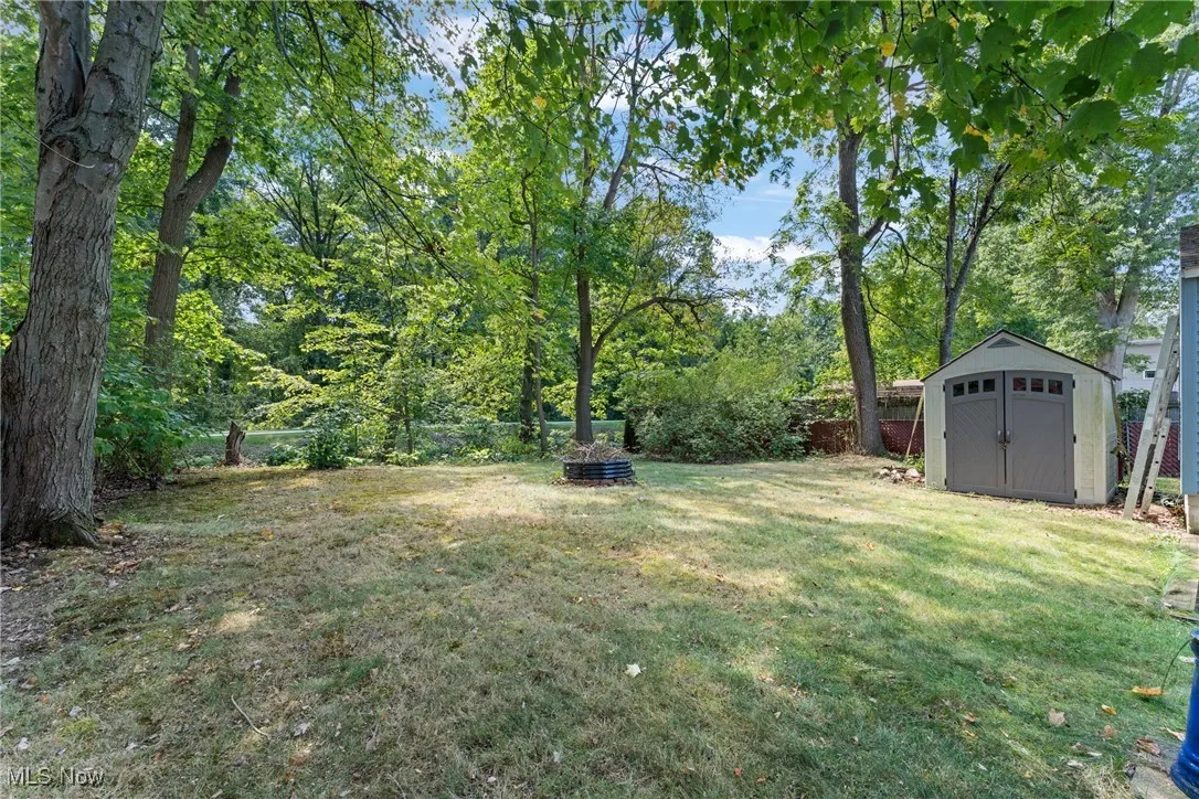 Fenced backyard featuring a shed and view of scattered trees