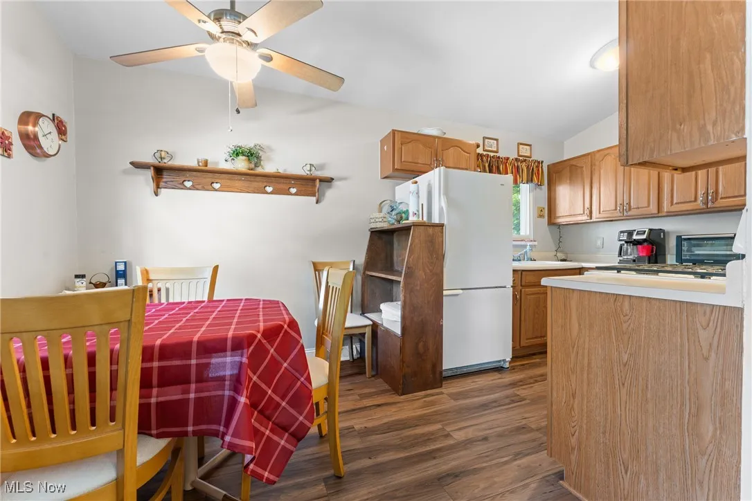 Kitchen featuring light countertops, dark wood finished floors, freestanding refrigerator, brown cabinets, and vaulted ceiling