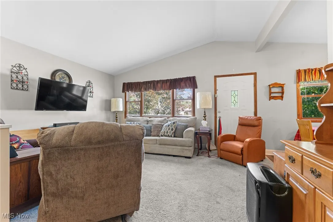 Carpeted living area with lofted ceiling
