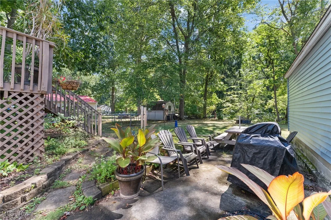 View of patio / terrace with stairs, a wooden deck, and view of wooded area